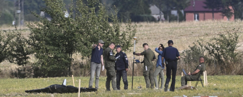 Полиция и военная полиция забирают части поврежденного БПЛА, сбитого польскими властями на месте происшествия в Вогине, Польша