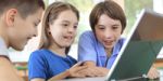 Schoolchildren having fun on laptops at classroom.