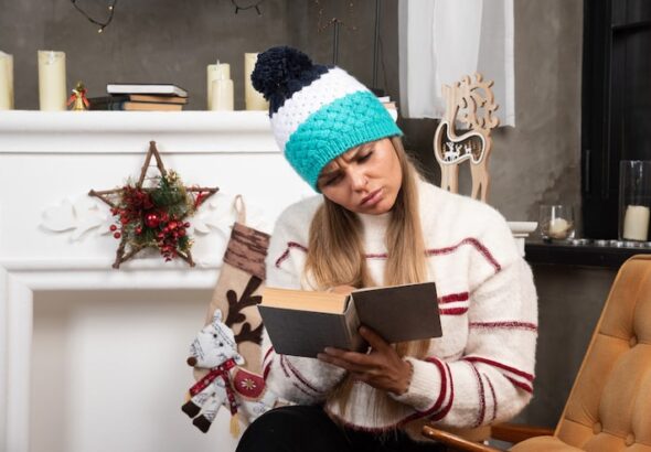 blonde-woman-reading-interesting-book-near-fireplace_114579-81067