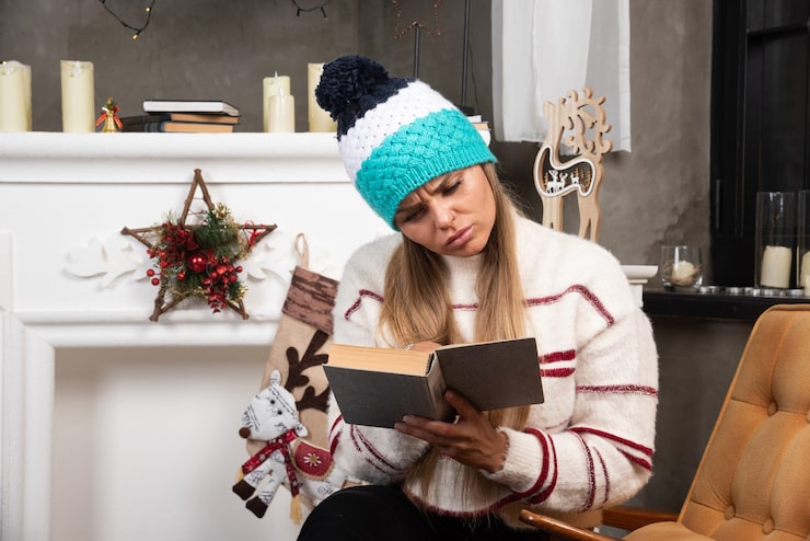 blonde-woman-reading-interesting-book-near-fireplace_114579-81067