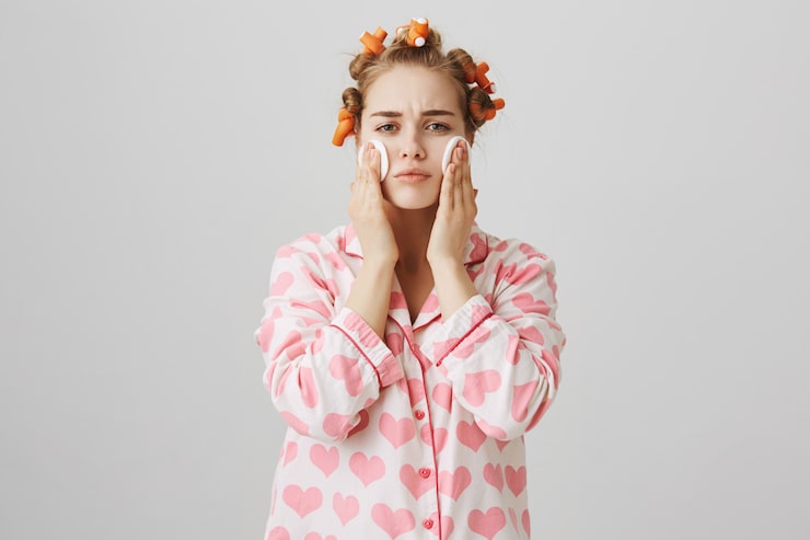 cute-girl-apply-cleanser-before-sleep-with-cotton-pad-wearing-hair-curlers-pyjama_176420-20088