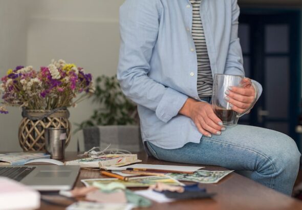 unrecognisable-woman-sitting-messy-desk_23-2148372131