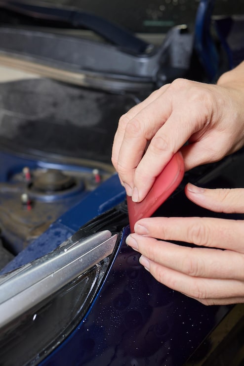 worker-applies-protective-film-antigravity-protective-coating-car-headlight-details-car_152904-44484
