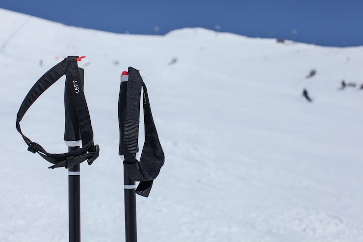 detail-ski-poles-hand-grip-with-blurred-piste-with-skiers-deep-blue-sky-background_692357-1004