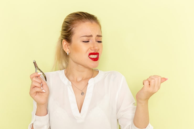 front-view-young-attractive-female-white-shirt-fixing-her-nails-getting-hurt-green-surface_140725-64165